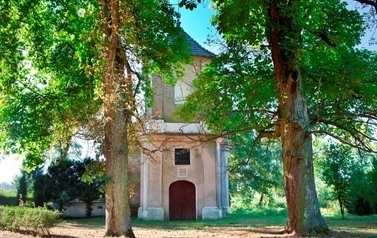 Osłonięty drzewami budynek kaplicy murowanej