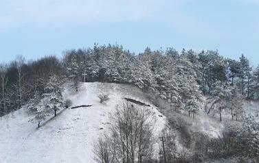 Widok an wzniesienie morenowe, pokryte śniegiem, na szczycie widoczny krzyż