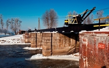 Zimowa sceneria, widok na fragment rzeki z budowlą hydrotechniczną 