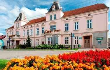 Przednia elewacja r&oacute;żowego budynku będącego siedziba Urzędu Gminy w Drawsku