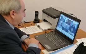 Na zdjęciu starosta czarnkowsko-trzcianecki siedzący za biurkiem, przed nim laptop; na monitorze uczestnicy zdalnego konkursu/spotkania