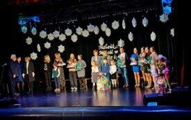 Pomieszczenie; na scenie stoją wyr&oacute;żnione zespoły. W rękach trzymają dyplomy i nagrody.