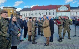 Plener; na pierwszym planie pułkownik gratulujący młodej żołnierce wyr&oacute;żnienia za osiągnięcia podczas szkolenia.