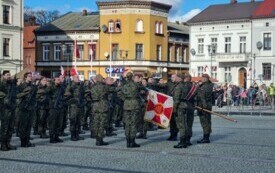Plener; najważniejszy moment uroczystości - złożenie przysięgi, wybrani żołnierze stoją naprzeciw sztandaru z wyciągniętymi ku niemu palcami.