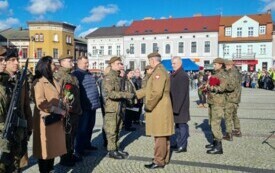 Plener; na pierwszym planie pułkownik gratulujący młodemu żołnierzowi wyr&oacute;żnienia za osiągnięcia podczas szkolenia.