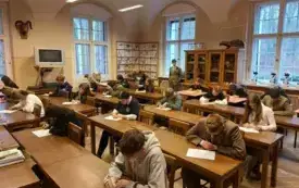 Pomieszczenie, klasopracownia, w sali rozstawione wypchane zwierzęta. Przy ławkach uczniowie, piszą test, wszyscy pochylają głowy nad kartkami. Przy oknie na parapecie mikroskopy.