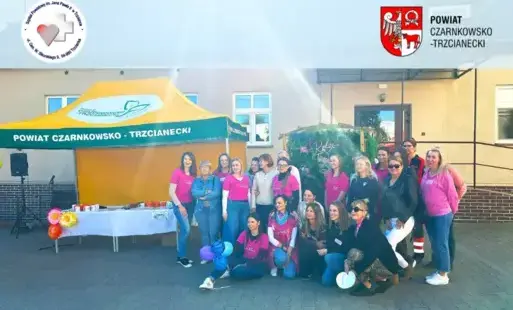 Zdjęcie grupowe w plenerze, grupa ludzi z lewej strony, z prawej strony stoi żółto-zielony namiot z napisem: powiat czarnkowsko-trzcianecki